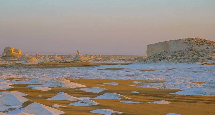 Formations rocheuses blanches dans un vaste paysage désertique.