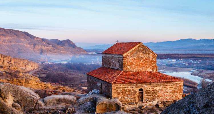 Historische kapel op een rotsachtig landschap met uitzicht op een vallei.