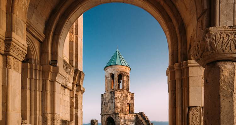 Kloostertoren omlijst door een boog met heldere hemel.