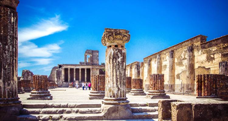 Ancient Roman ruins with sky and clouds.