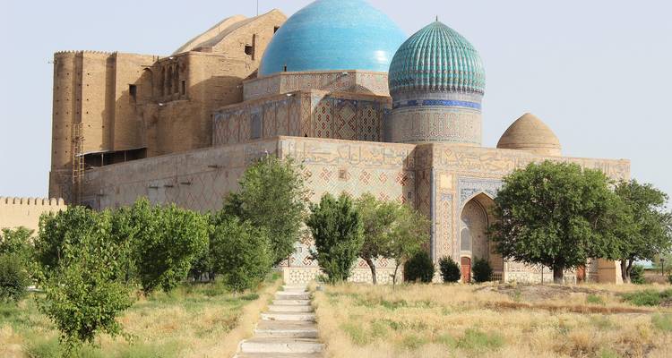 Historisches Gebäude mit blauen Kuppeln umgeben von Grün.