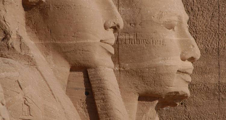 Close-up profile of colossal pharaonic statues carved into sandstone at Abu Simbel.