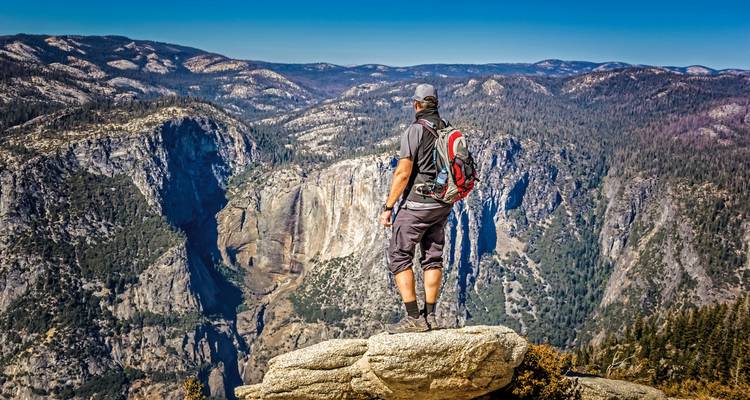 Wanderer, der über eine weite Berglandschaft blickt.