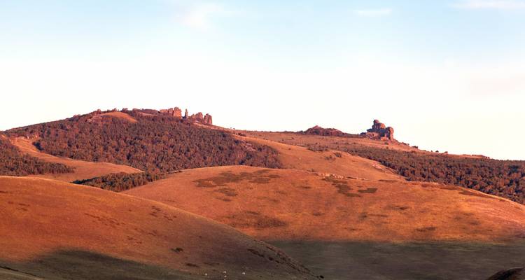 Collines ondulantes et formations rocheuses baignées dans une lumière chaude.