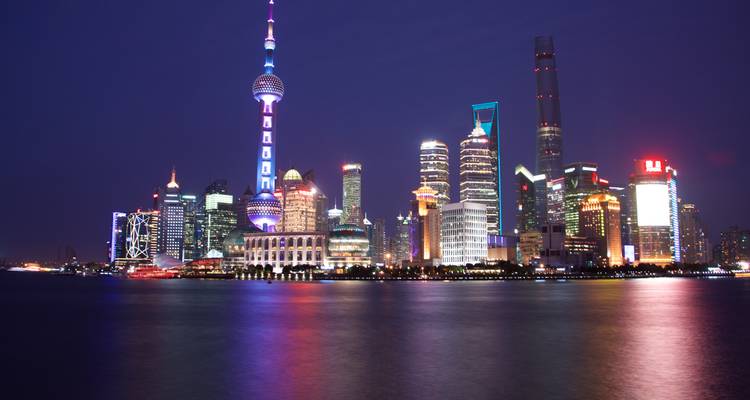 Night view of the Shanghai skyline with illuminated skyscrapers.