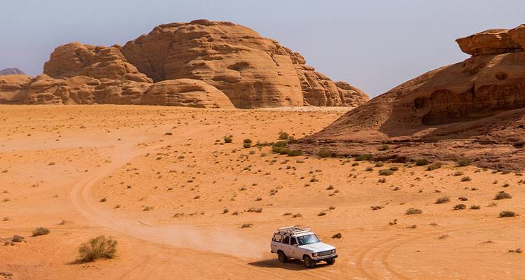 Un vehículo conduciendo a través de un desierto con formaciones rocosas.
