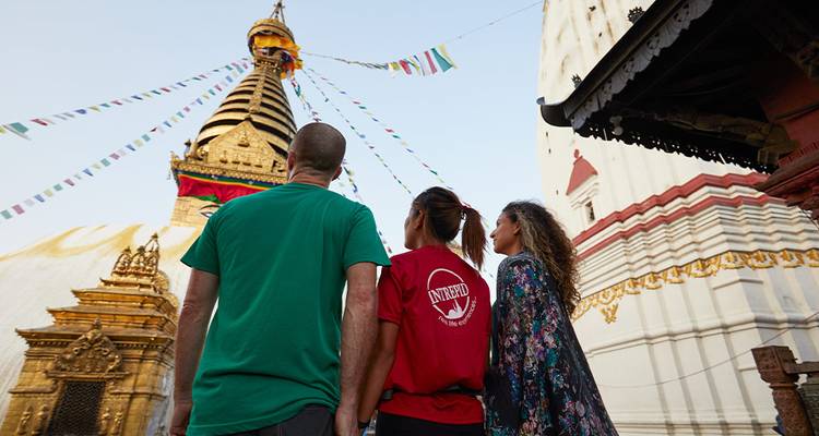 People observing a religious site with flags and intricate architecture.