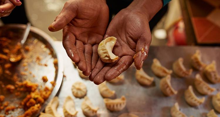 Hands making dumplings with filling visible.