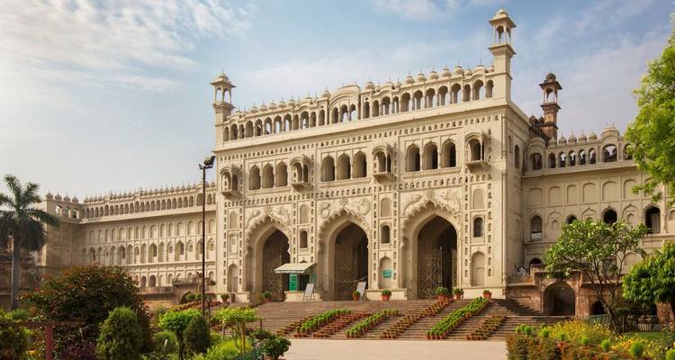 Un bâtiment en pierre blanche avec des jardins verts devant.