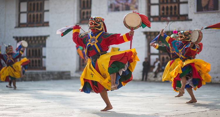 Bailarines tradicionales butaneses en trajes coloridos interpretando una danza cultural.