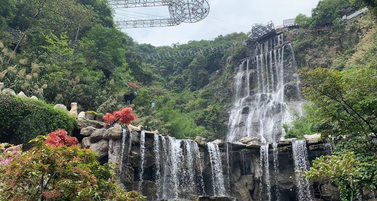 Waterval die naar beneden stroomt langs een rotsachtige klif te midden van weelderige vegetatie.