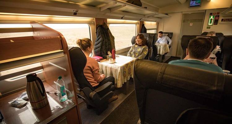Interior of a train with passengers sitting at tables.