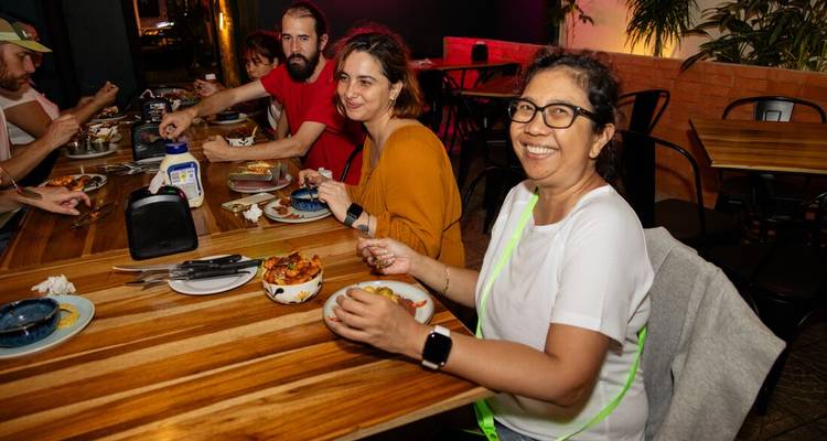 Travelers enjoying a casual Costa Rican meal together at a wooden restaurant table.