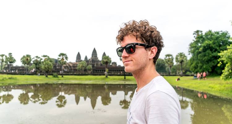 Person smiling in front of a temple with a large reflection pool.