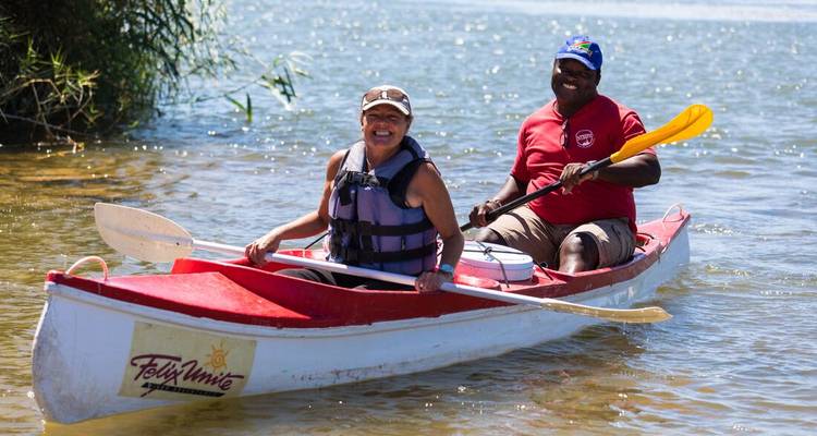 Deux personnes faisant du canoë sur une rivière sous un ciel dégagé.