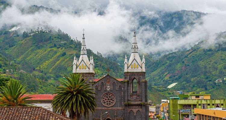 Mensen op een levendig plein met een historisch gebouw en bergen op de achtergrond.