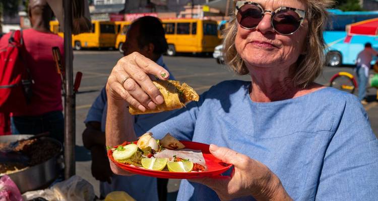 Woman holding a taco at an outdoor food market.