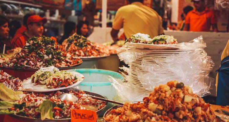 Food market scene with various dishes and people.