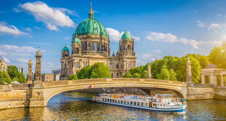 Barocke Kathedrale an einem Fluss mit einem Kreuzfahrtschiff unter der Brücke.
