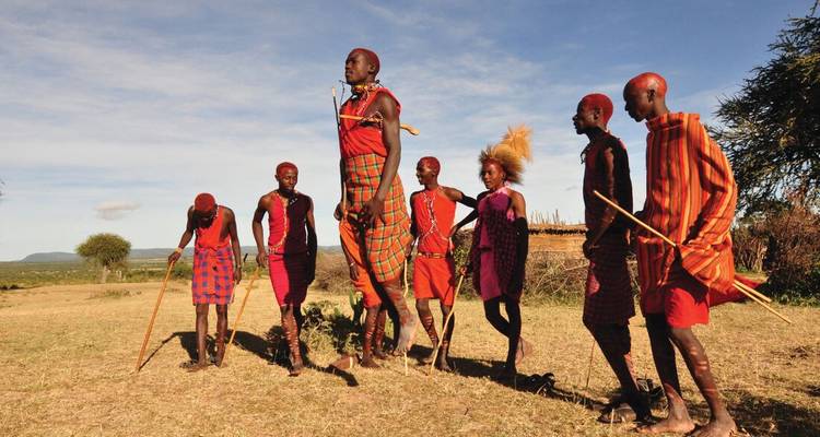 Aldeanos maasai vestidos con ropa tradicional de colores brillantes realizando un baile de saltos en la pradera