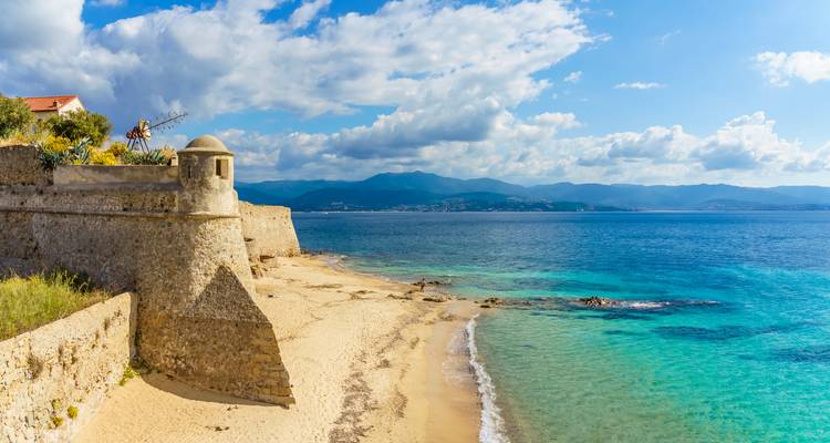Fortaleza costera con una playa de arena y mar cristalino.