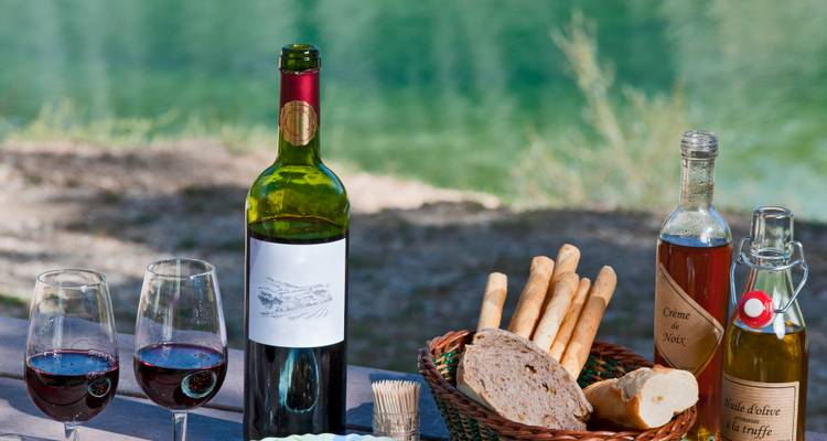 Preparación de picnic con vino, pan y un paisaje escénico de fondo.