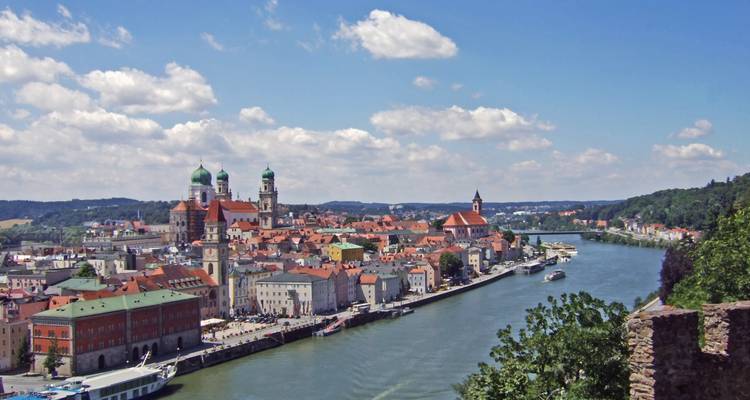 Waterfront view of a city with red-roofed buildings and cathedral.