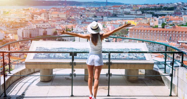 Person overlooking a city from a viewpoint with open arms.