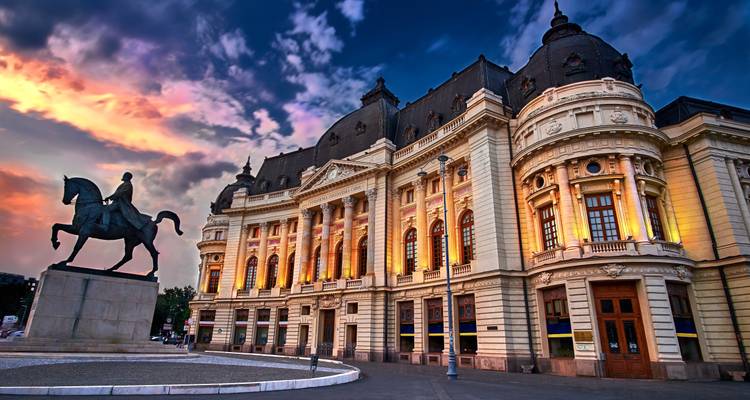 Historisches Gebäude in Bukarest bei Sonnenuntergang mit Reiterstatue.