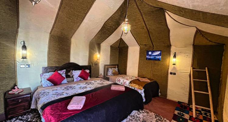 Cozy interior of a desert camp with beds and lanterns.