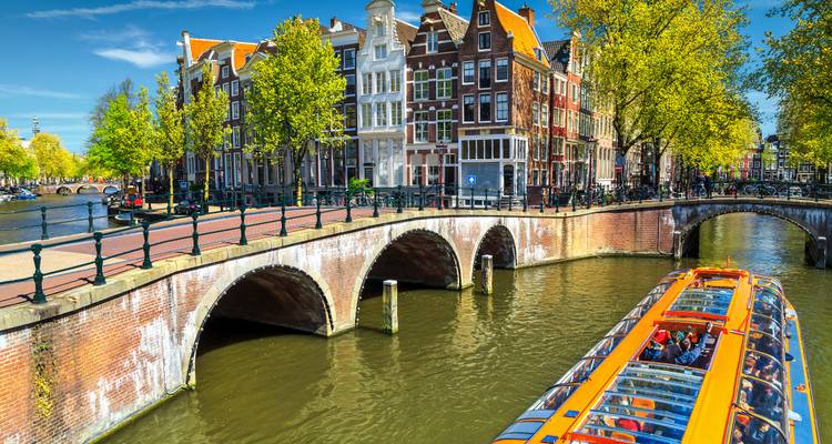 Recorrido en canal con casas a lo largo de un pintoresco canal en Ámsterdam.