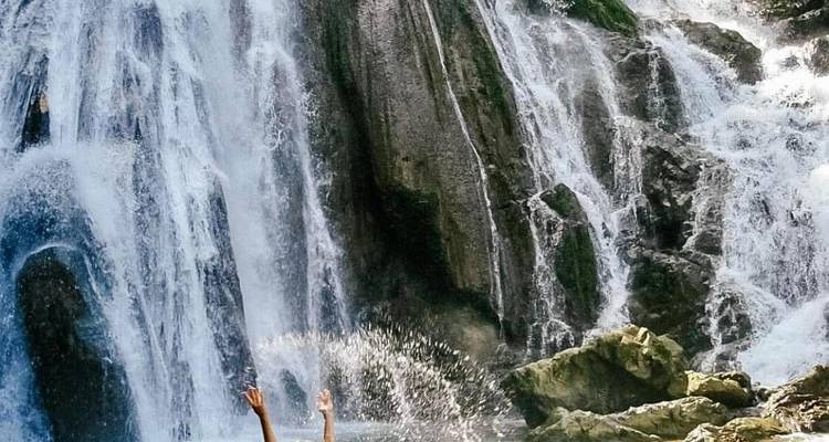 People enjoying a waterfall with splashing water.