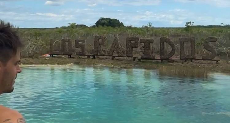 Personne regardant un lagon avec un panneau indiquant 'Les Rapides'.
