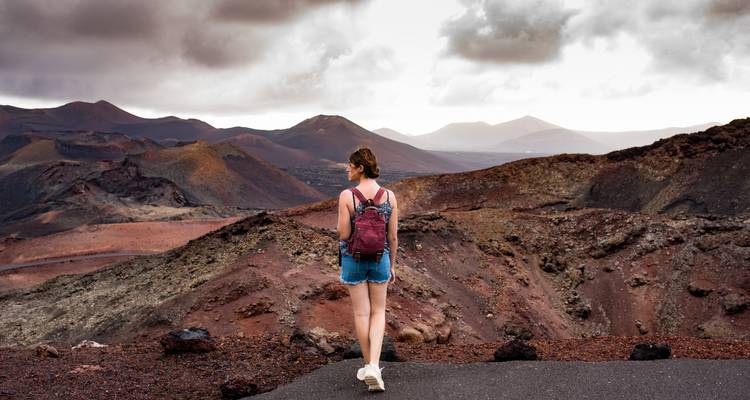 Personne explorant un paysage volcanique avec un ciel sombre.