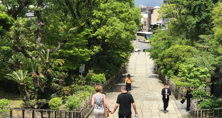 People walking down a stone path surrounded by greenery.