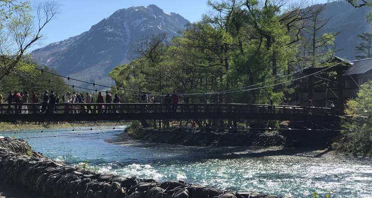 A bridge over a river with mountains in the background.