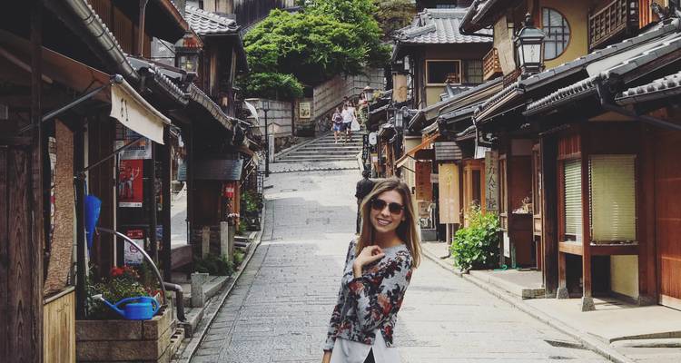 A person posing on a traditional street with wooden buildings.