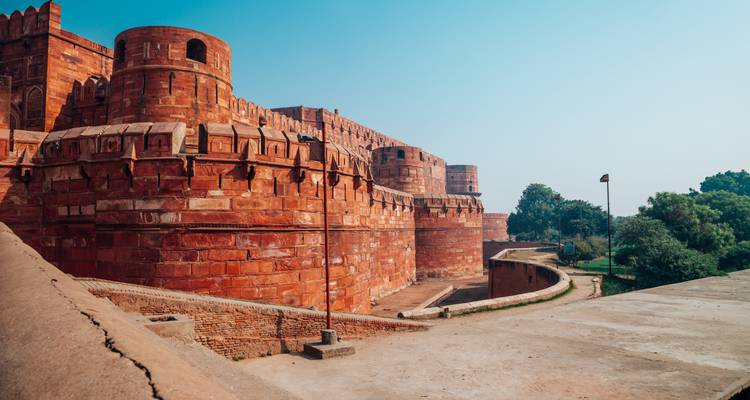 Exterior view of the red sandstone Agra Fort under clear skies.