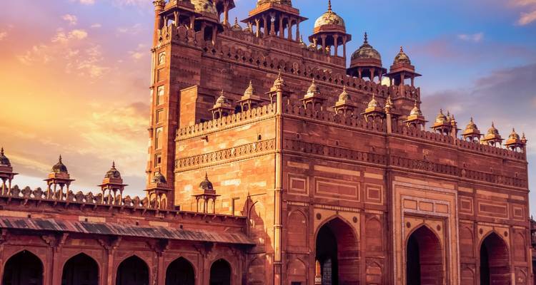 Sunset view of an ancient red sandstone palace with intricate carvings.
