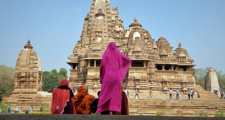 Individuals in traditional attire near an ornately carved temple.