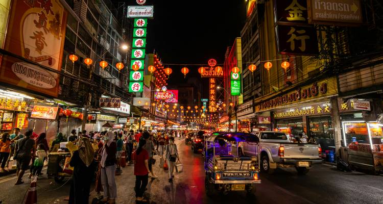 A vibrant night market scene in Bangkok with crowds of people.