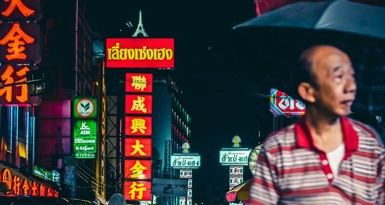 A person standing in front of colorful neon signs at night.