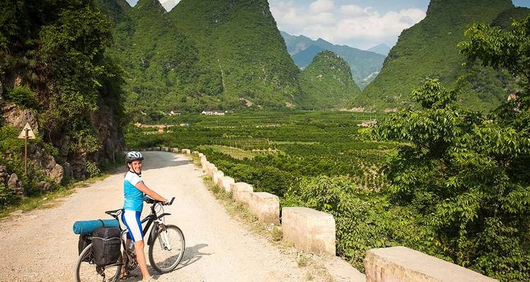 Fietser op een schilderachtig pad met bergen op de achtergrond.