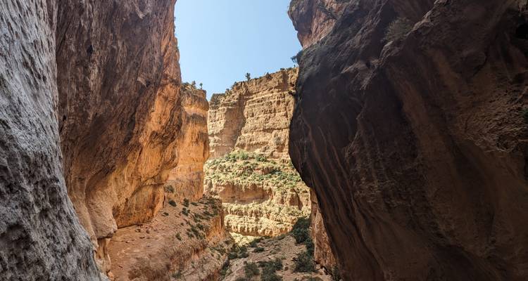 Canyon walls with a view of rocky cliffs under a blue sky.