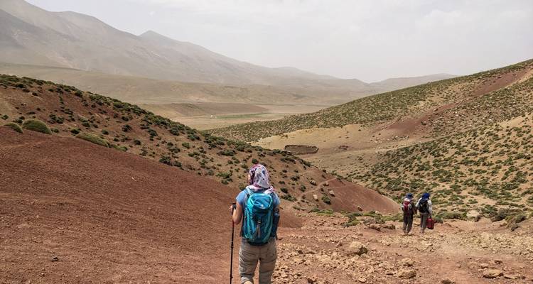 Hikers walking through a dry, hilly landscape.