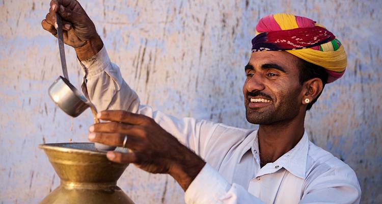 Homme versant une boisson avec un sourire chaleureux.
