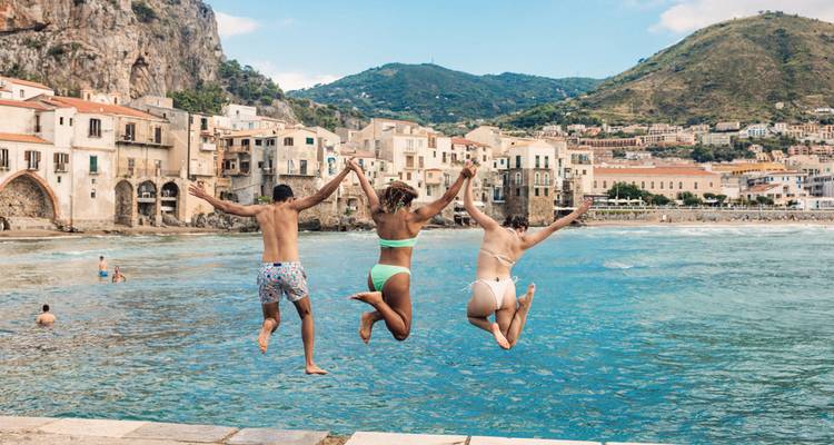 Drie mensen die in de zee springen vanuit een kustplaats.