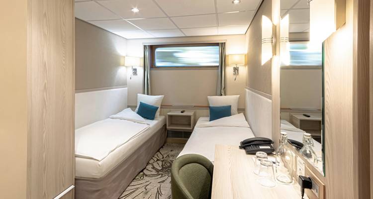 Interior of a compact cruise cabin with small twin beds.