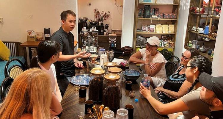 Un groupe de personnes assises à une table à l'intérieur, engagées dans une discussion.