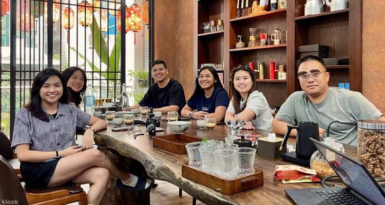 Groupe assis autour d'une table en bois à l'intérieur avec des articles de café présents.
